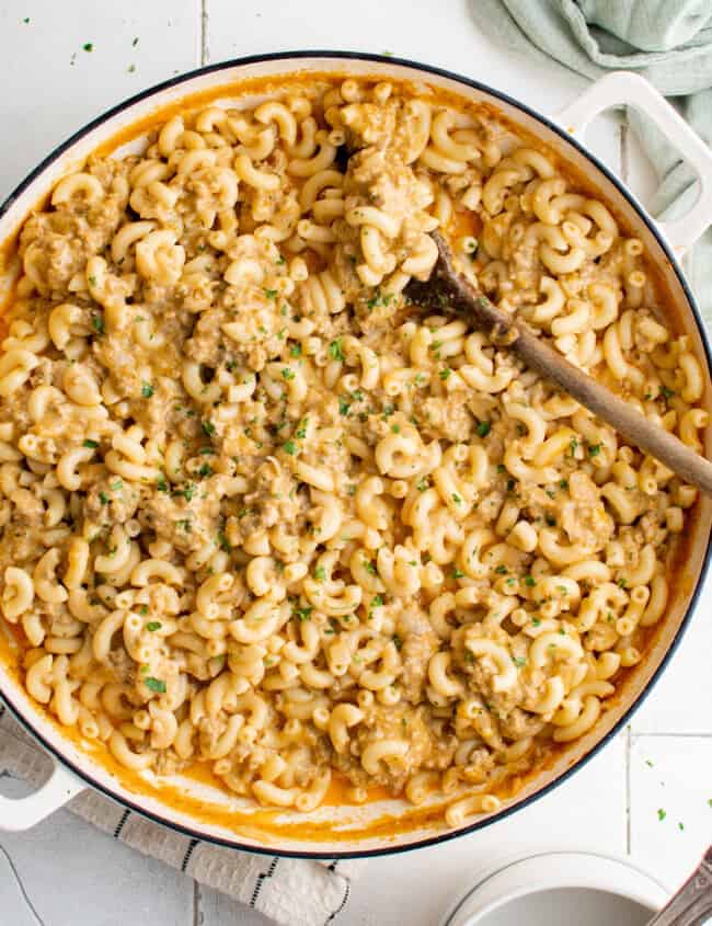 overhead view of hamburger helper in a white pan with a wooden spoon.