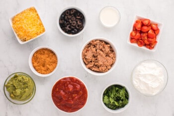overhead view of ingredients for 7 layer dip cups in white bowls.