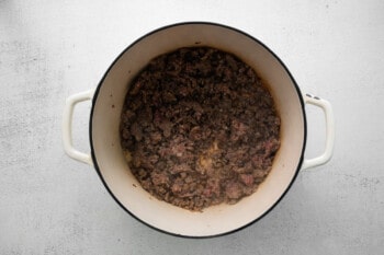 browned sausage in a white dutch oven.
