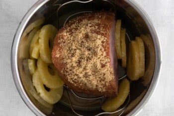 ham topped with brown sugar and pineapple slices in an instant pot.