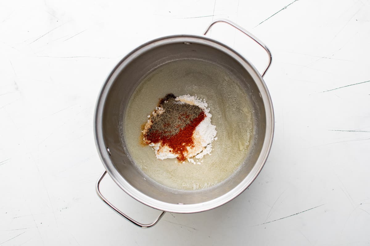a metal pot with spices in it on a white surface.