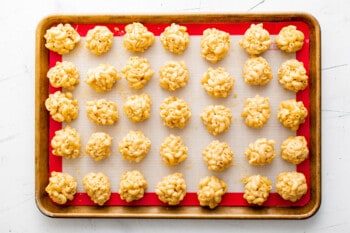 balls of Mac and cheese lined up on a baking tray, before coating in breadcrumb mixture