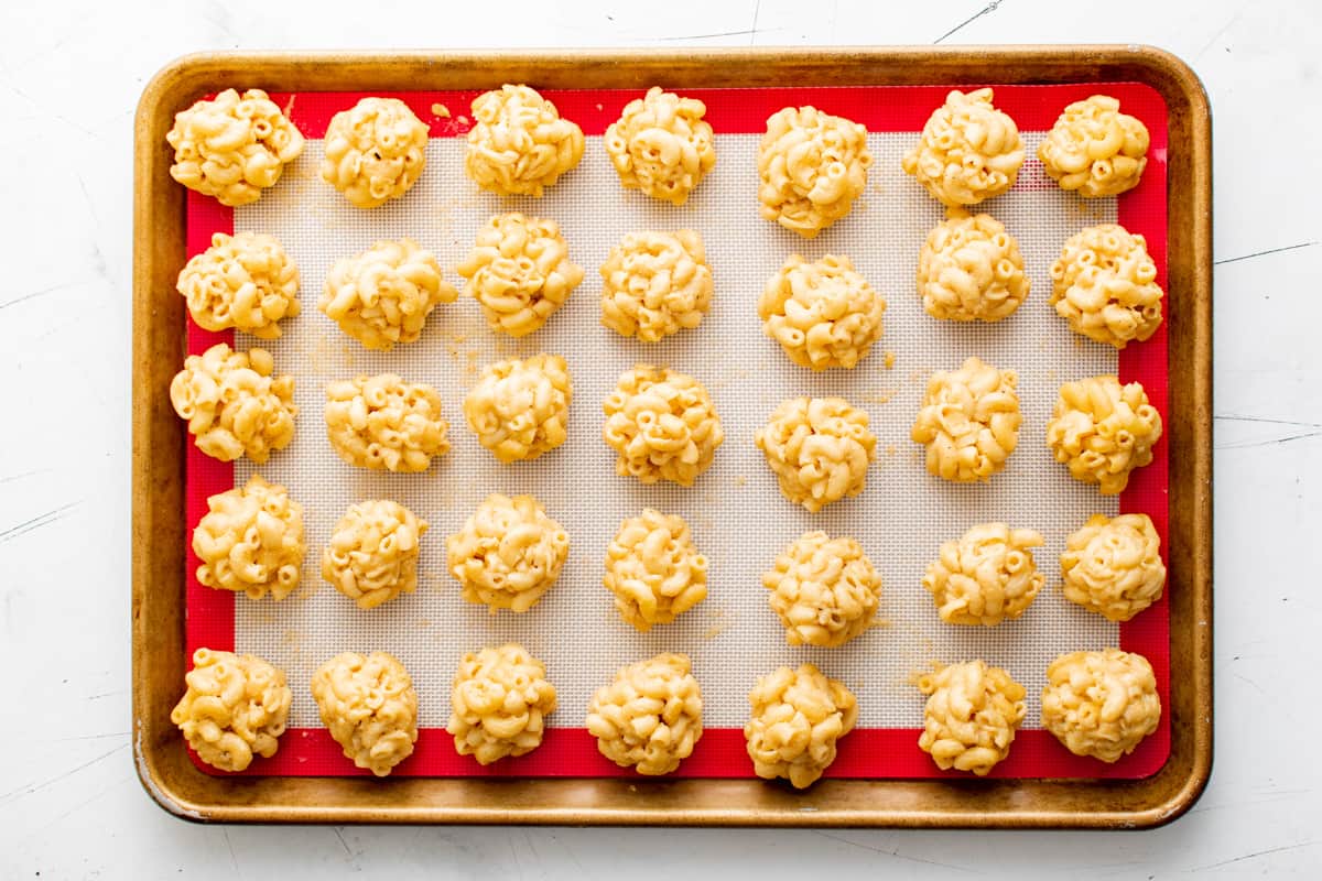 balls of Mac and cheese lined up on a baking tray, before coating in breadcrumb mixture