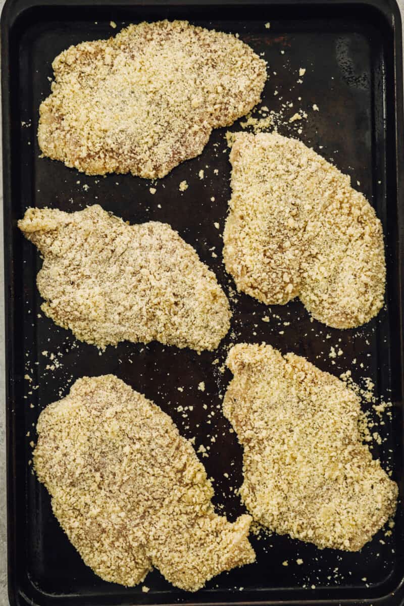 Breaded chicken breasts on a baking pan.