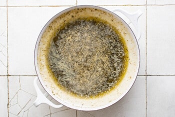 a white dish with a bowl of oil on a tiled floor.