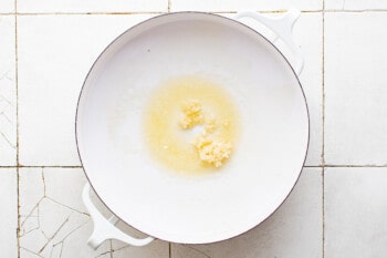 a white bowl with a yellow liquid in it on a tiled floor.