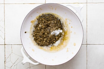 a white bowl filled with a mixture of spices on a tiled floor.