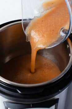 an orange liquid being poured into an instant pot.