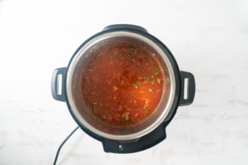 an instant pot filled with tomato sauce on a white surface.