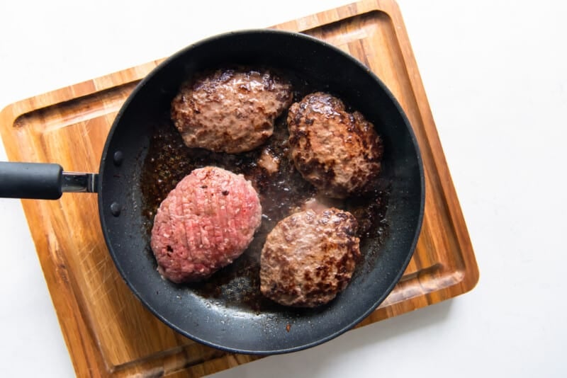 burger patties cooking in a skillet