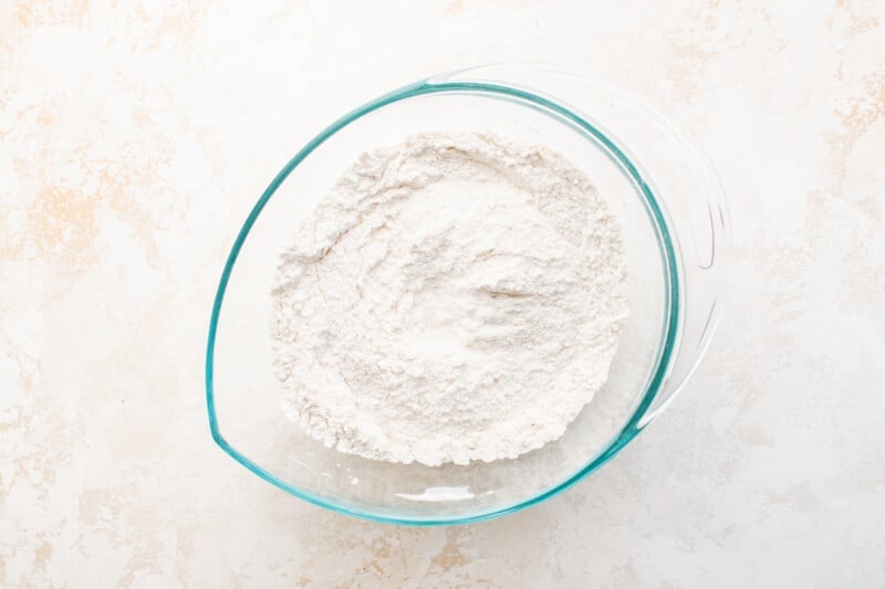 flour in a glass bowl on a white background.