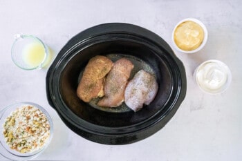 seasoned chicken breasts in a black crockpot.