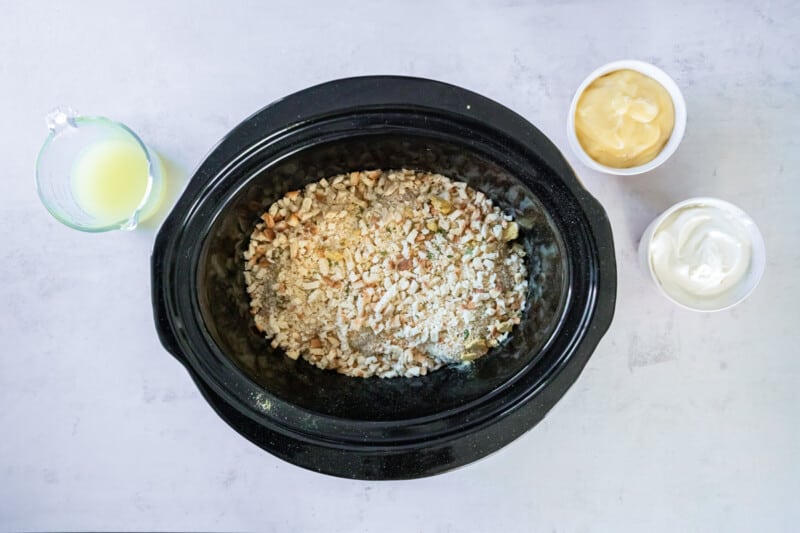 stuffing mix poured over chicken breasts in a black crockpot.