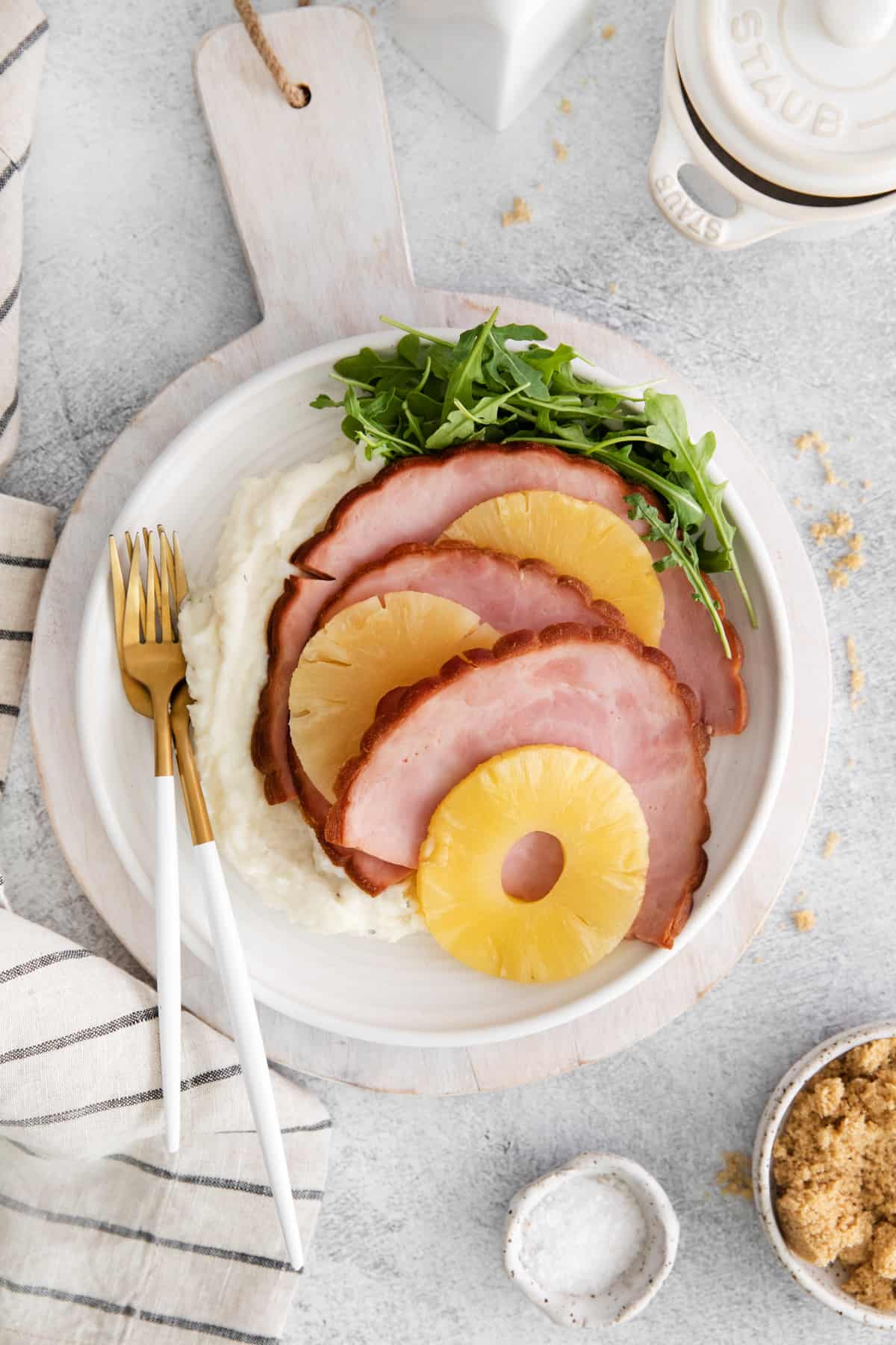 overhead view of instant pot pineapple brown sugar ham on a white plate with a fork and knife.