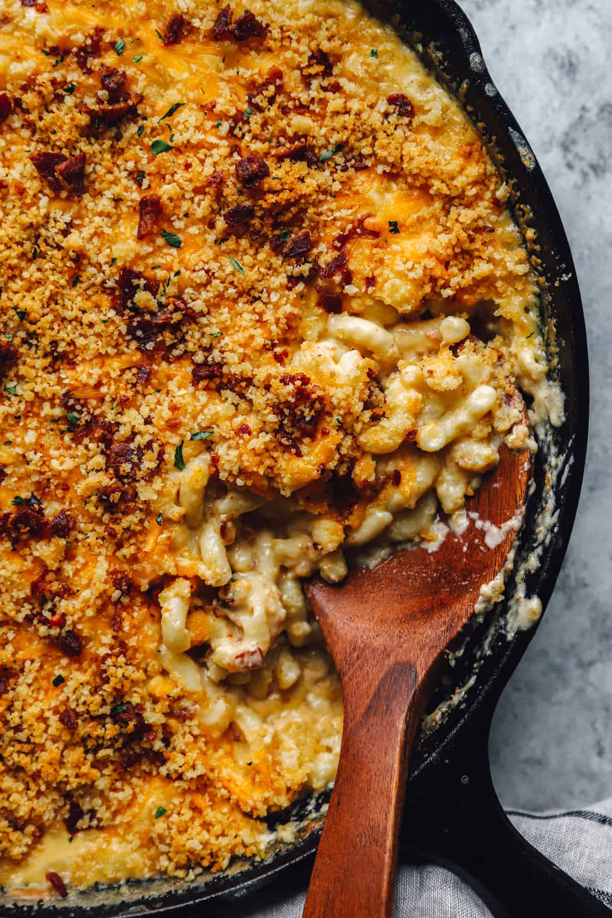 wooden spoon digging into a skillet of Mac and cheese
