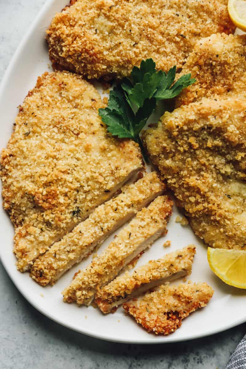 parmesan crusted chicken, one is partially cut into thin slices