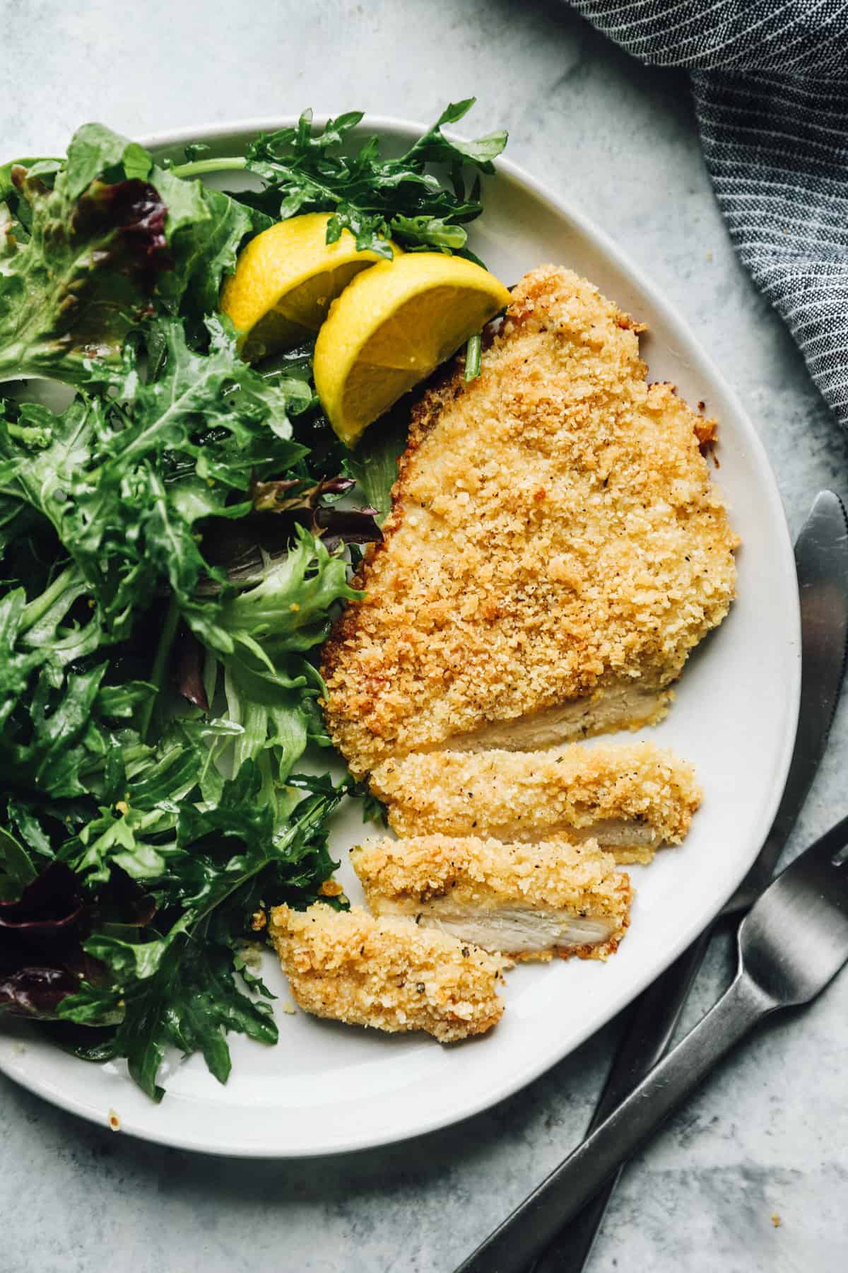 dinner plate with parmesan crusted chicken breast and greens