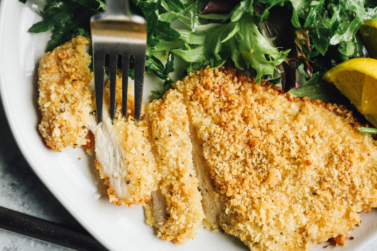 close up on parmesan crusted chicken breast, partially cut into slices