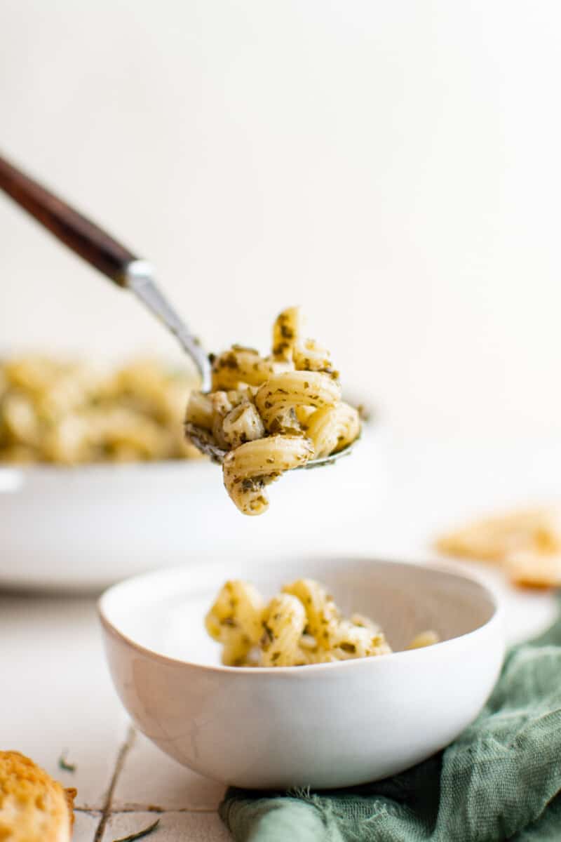 spoon scooping up pesto cavatappi out of a bowl