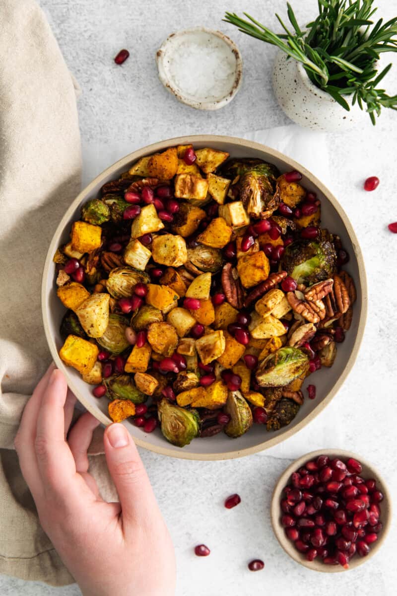 hand reaching towards a bowl of air fryer roasted veggies