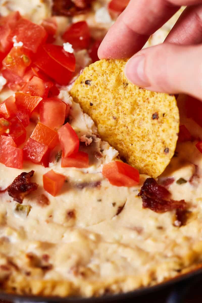 dipping a tortilla chip into hot bacon feta dip