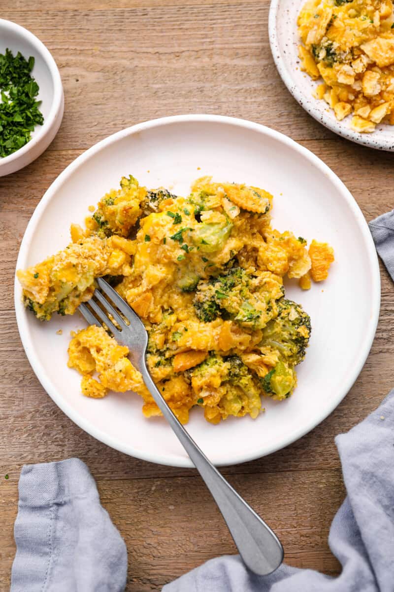 broccoli cheese casserole on a white plate with a fork.