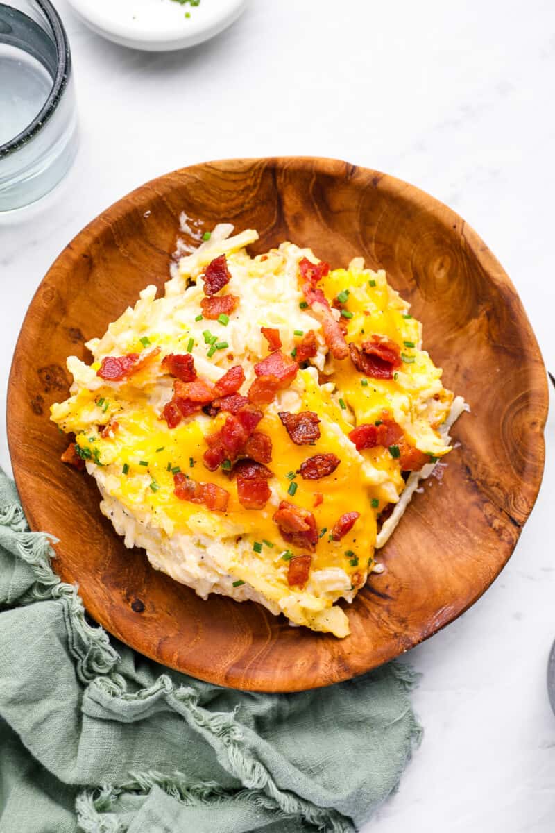 overhead view of crockpot cheesy hashbrown potatoes in a wooden bowl.