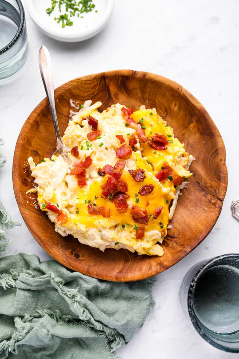 overhead view of crockpot cheesy hashbrown potatoes in a wooden bowl with a fork.