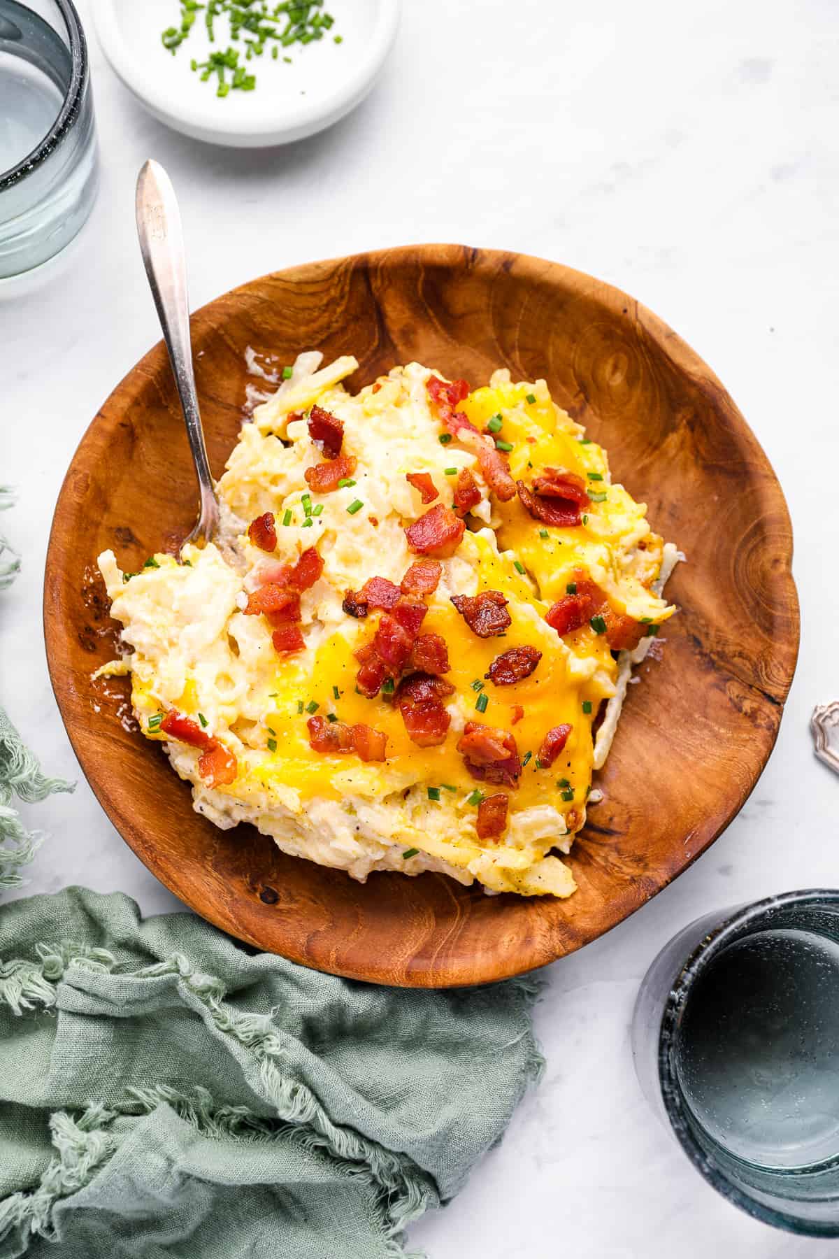 overhead view of a serving of crockpot potato casserole in a wooden bowl with a spoon.