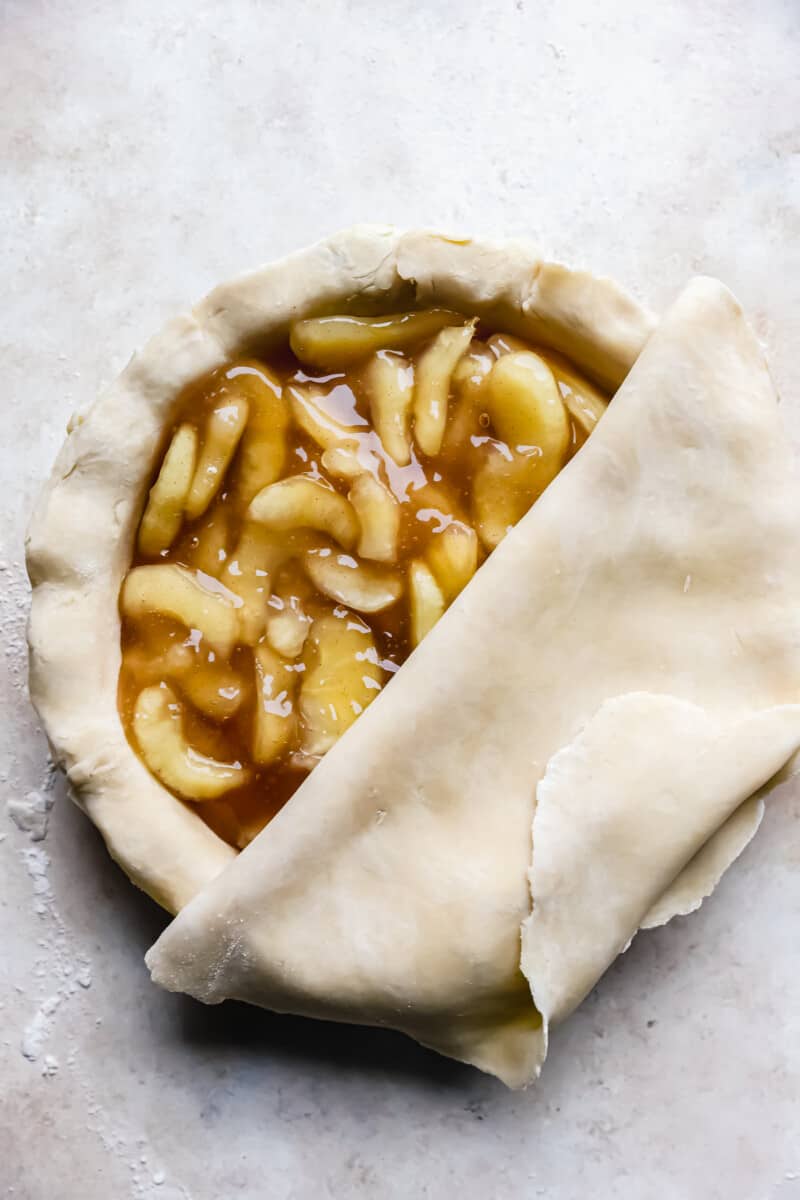 rolling pie crust on top of an apple pie