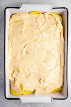 cheese sauce poured over layers of potatoes in a 9x13 baking pan.