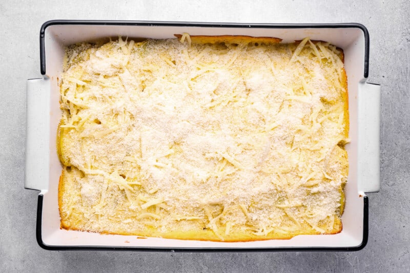 parmesan cheese sprinkled over au gratin potatoes in a 9x13 baking pan.