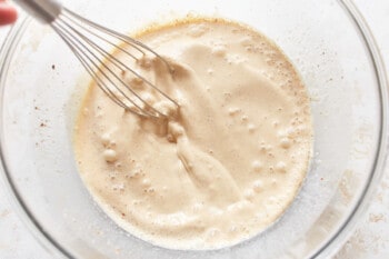 a person mixing ingredients in a bowl with a whisk.