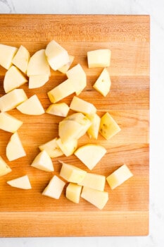 chopped potatoes on a wooden cutting board.