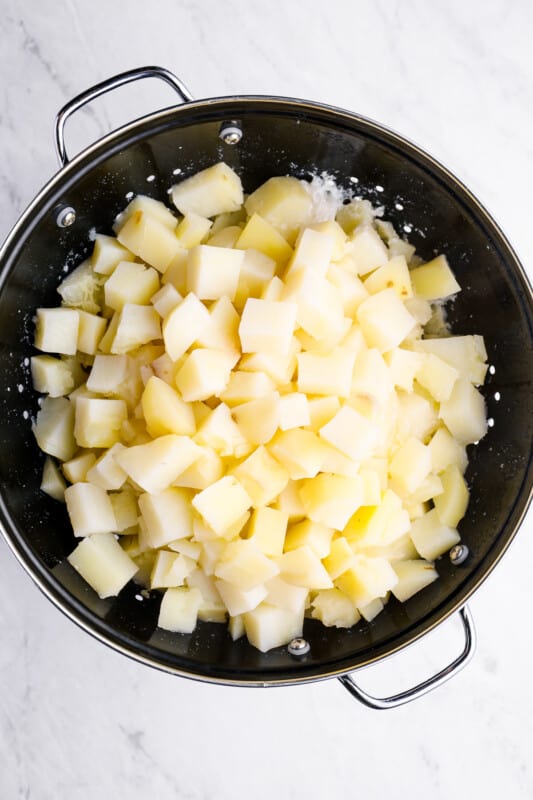 mashed potato cubes draining in a colander.