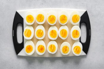 boiled eggs cut in half and lined up on a cutting board