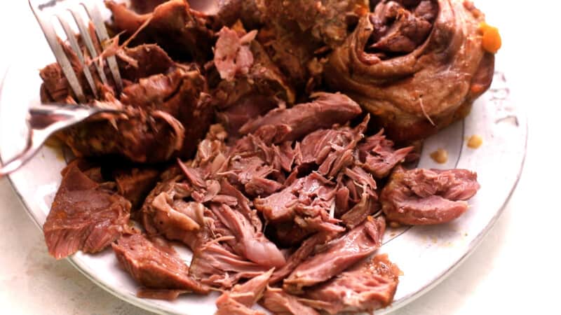 shredding meat on a plate with two forks