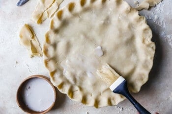 brushing milk on top of a pie crust