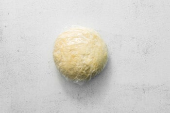 ball of pie crust dough wrapped in plastic wrap