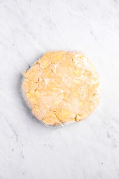 overhead view of sweet potato pie dough wrapped in plastic wrap.