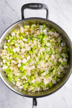 overhead view of onion, celery, and garlic cooking in a sauté pan.