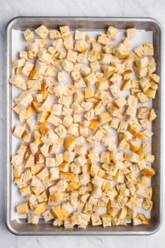 overhead view of cubes of bread on a baking sheet.