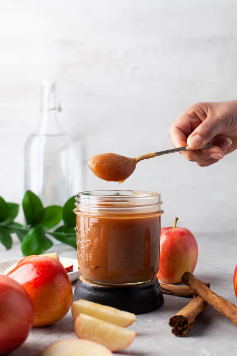 hand scooping up apple butter out of a jar