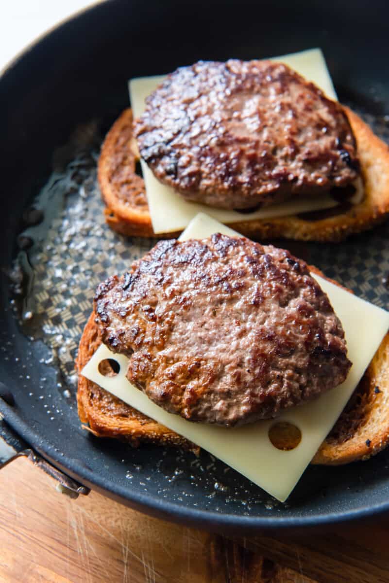 patty melts cooking in a skillet