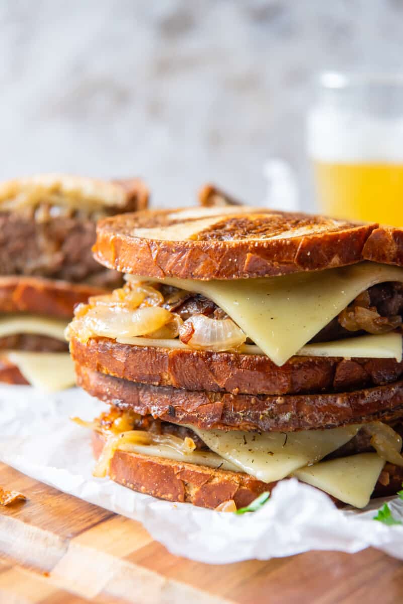 patty melts with onion and Swiss cheese, stacked on top of each other
