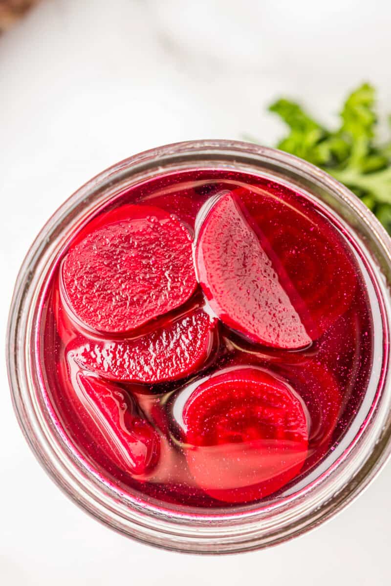 overhead view of pickled beets in a wide mouth glass jar.