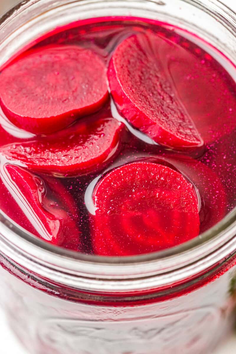 close up view of pickled beets in a wide mouth glass jar.