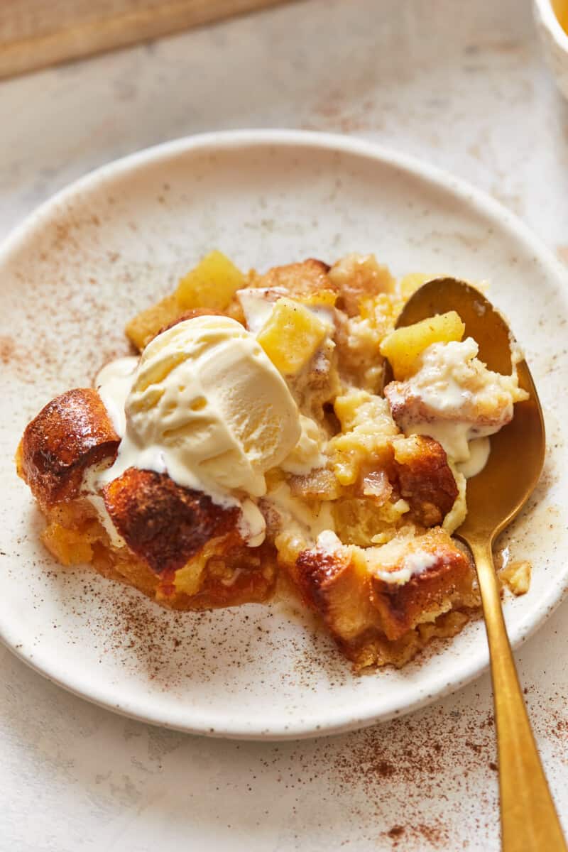 a plate of pineapple bread pudding with ice cream and a spoon