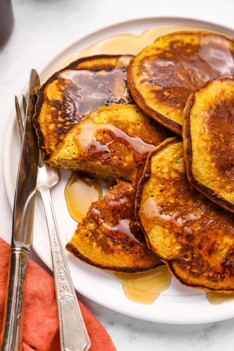 close up on a plate of pumpkin pancakes with a fork and knife set on the side