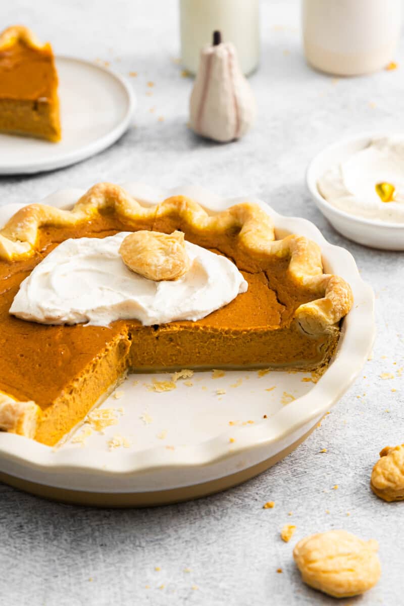 classic pumpkin pie in a ceramic pie dish, with a couple of sliced removed